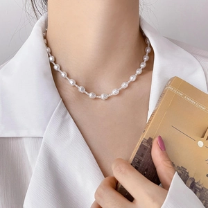 Close-up of irregular baroque pearl necklace worn by a model in a literary style