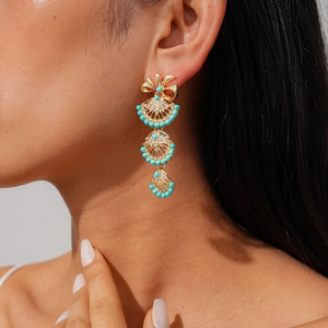 Detailed view of long fan-shaped earrings with blue beads on a model's ear