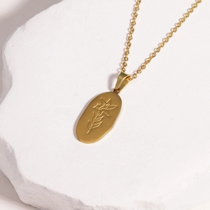 Detail shot of a gold irregular oval pendant with lily floral engraving on stone