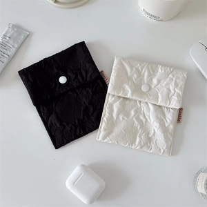 Detail showing white and black floral textured fabric pouches with snap button closure