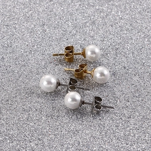 Macro shot of white pearl earrings with gold and silver stainless steel studs and backings