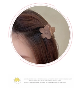Close-up of a matte brown flower hair claw clip worn on a woman's brown hair