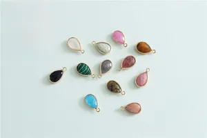Flat lay of colorful teardrop gemstone pendants with metal frames in 12 assorted colors