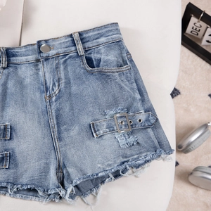 Detail of light blue denim shorts featuring metal ring buckle and frayed hem design