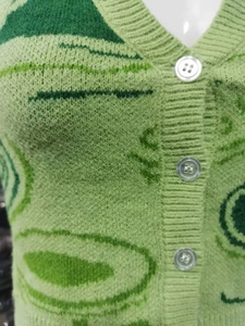 Dettaglio del gilet in maglia verde con motivo jacquard floreale vintage e bottoni