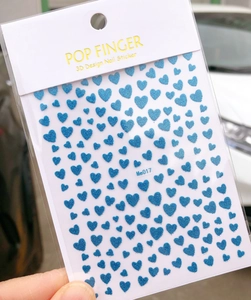 Detail of 3D blue glitter heart nail art stickers with frosted texture and gold accents