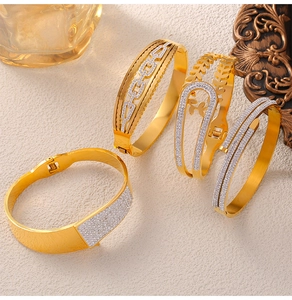 Détails de quatre bracelets géométriques dorés ornés de strass sur un fond texturé