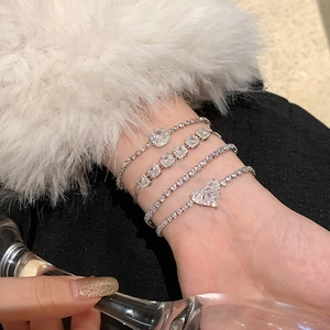 Gros plan de bracelets argentés empilés avec des zircons et des breloques en cœur