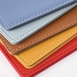 Close-up of stacked PU leather passport covers with detailed white stitching in five colors