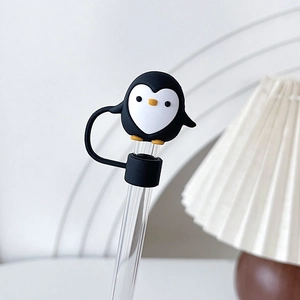 Joli embout de paille pingouin noir et blanc en silicone sur une paille en verre clair