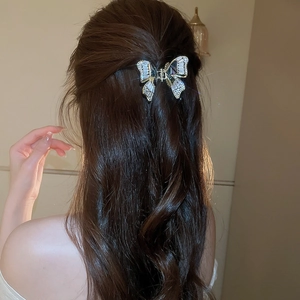 Elegante molletta a farfalla con zirconi e madreperla indossata su capelli mossi