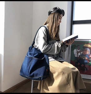 Deep blue denim large capacity tote bag with stitching detail shown in a casual lifestyle setting