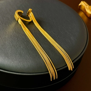 Close-up of golden long tassel ear clips on a black jewelry box for a stylish look