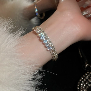 Detail of multilayer zircon bracelet on wrist with sparkling crystals and golden finish