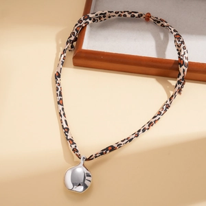 Détail d'un collier en tissu léopard avec un grand pendentif goutte en argent poli brillant