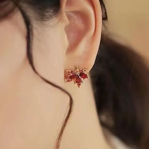 Vue latérale macro de boucles d'oreilles feuille d'érable avec pierres rouges