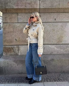 Detail of beige double-breasted cropped trench coat with waist belt and epaulettes