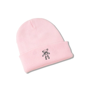 Gros plan détaillé du bonnet en maille rose avec broderie ours et revers classique