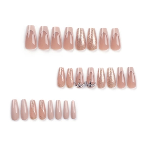 French nude press-on nails with gold glitter gradients and 3D rhinestones in coffin shape
