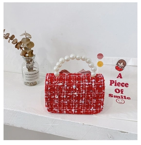 Detail of red tweed girls handbag featuring pearl handle and decorative pink bow