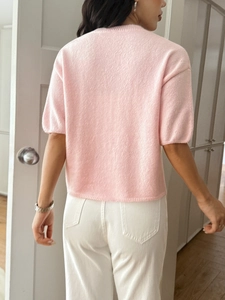 Rear view of a casual pink short-sleeved knit top showing texture and premium tailoring