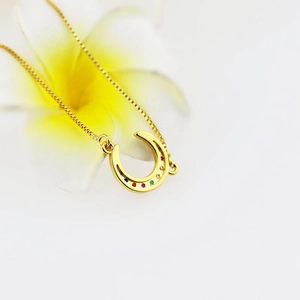 Macro view of gold horseshoe pendant with rainbow zircon stones and floral decoration