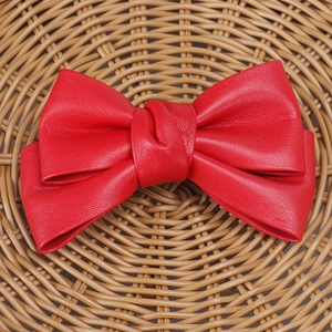 Detailed view of red PU leather bow hair clip with visible stitching and texture