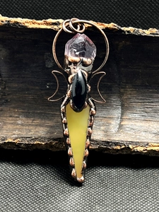 Macro detail of bronze pendant with amethyst, black agate and yellow gemstone