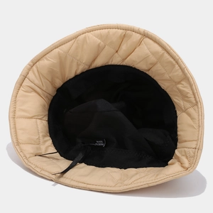Close-up of beige quilted bucket hat showing diamond stitching and black interior lining