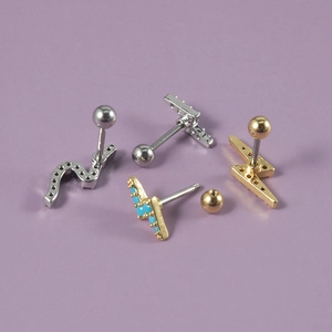Detailed close-up of lightning and wave ear studs with blue zircon on lavender background