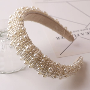 Elegant wide pearl headband featuring multi-sized white faux pearls on beige fabric
