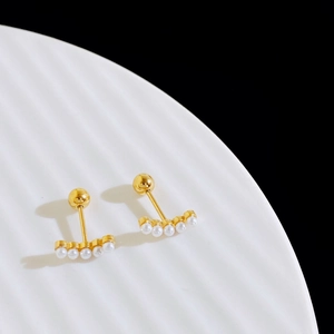 Detailed macro view of five white pearls set in gold-plated steel on a ceramic tray