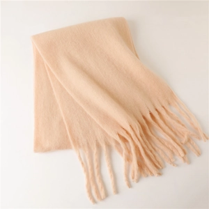 Gros plan sur l'écharpe d'hiver en mohair pêche avec de longues franges et maille douce
