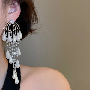 Close-up of dangling silver earrings with zircon waterdrop pearls on a model