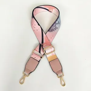 Detail view of ethnic graffiti print wide bag strap with pink leather and gold hardware