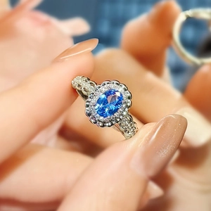Close-up of an oval sapphire ring with sparkling diamond pave set in silver metal