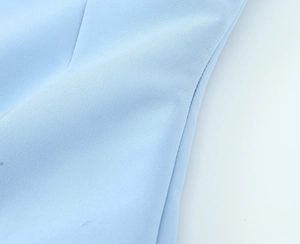 Close-up of light blue woven fabric detail on a stretch vest top with premium texture