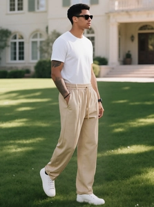 Dettaglio dei pantaloni beige da uomo con coulisse e sneakers bianche sul prato