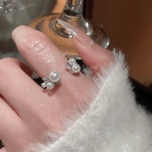 Detailed close-up of a silver open ring with pearls and pavé zircons on finger