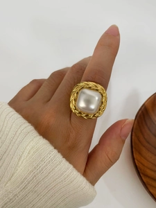 Detail of vintage gold ring with large square pearl inlay and woven metal edge decoration