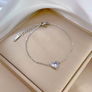 Close-up of heart-shaped zircon pendant on silver titanium steel bracelet in a jewelry box
