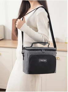 Woman wearing a large dark grey insulated lunch bag with adjustable shoulder strap