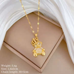 Detailed shot of golden crown bear necklace with sparkling zircons on silk background
