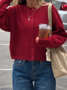Detail view of a women's red knit cardigan featuring a round neck and front button design