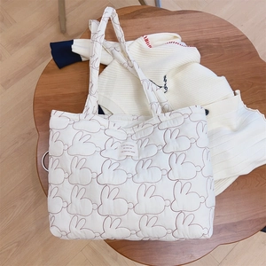 Detailed close-up of rabbit embroidery and quilted texture on a white tote bag