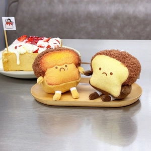 Close-up of cute plush toast keychains with sad expressions on a wooden tray