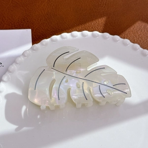 Detailed view of monstera leaf hair claw with pearlescent white finish and black veins