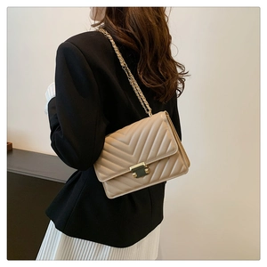 Detail of beige chevron stitched crossbody bag with gold chain strap and metal lock