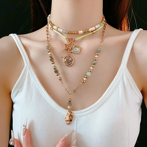 Detailed layered necklace with green beads, golden coins and vintage leaf pendants