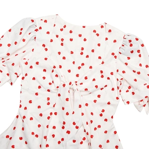 Détail de la robe d'été blanche à fleurs rouges avec encolure carrée et manches bouffantes